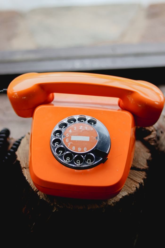 services-03 A vibrant orange rotary dial telephone showcasing retro design and vintage appeal.